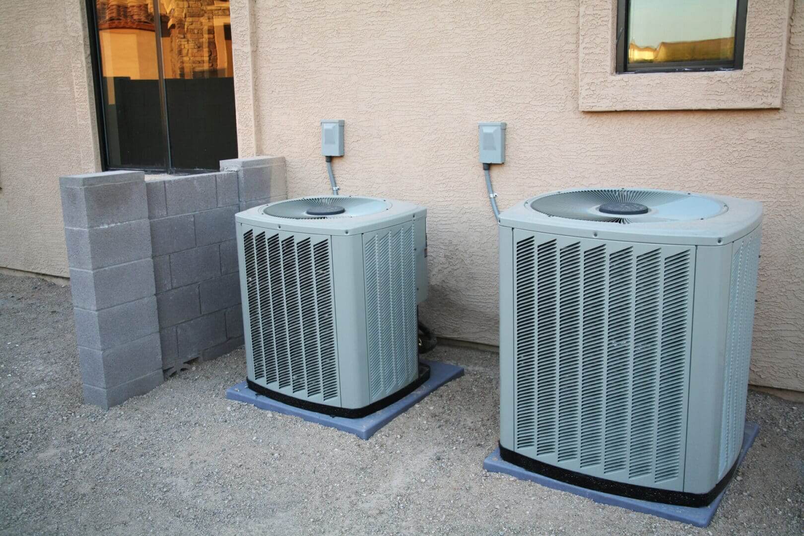 Two outdoor air conditioning units beside building.