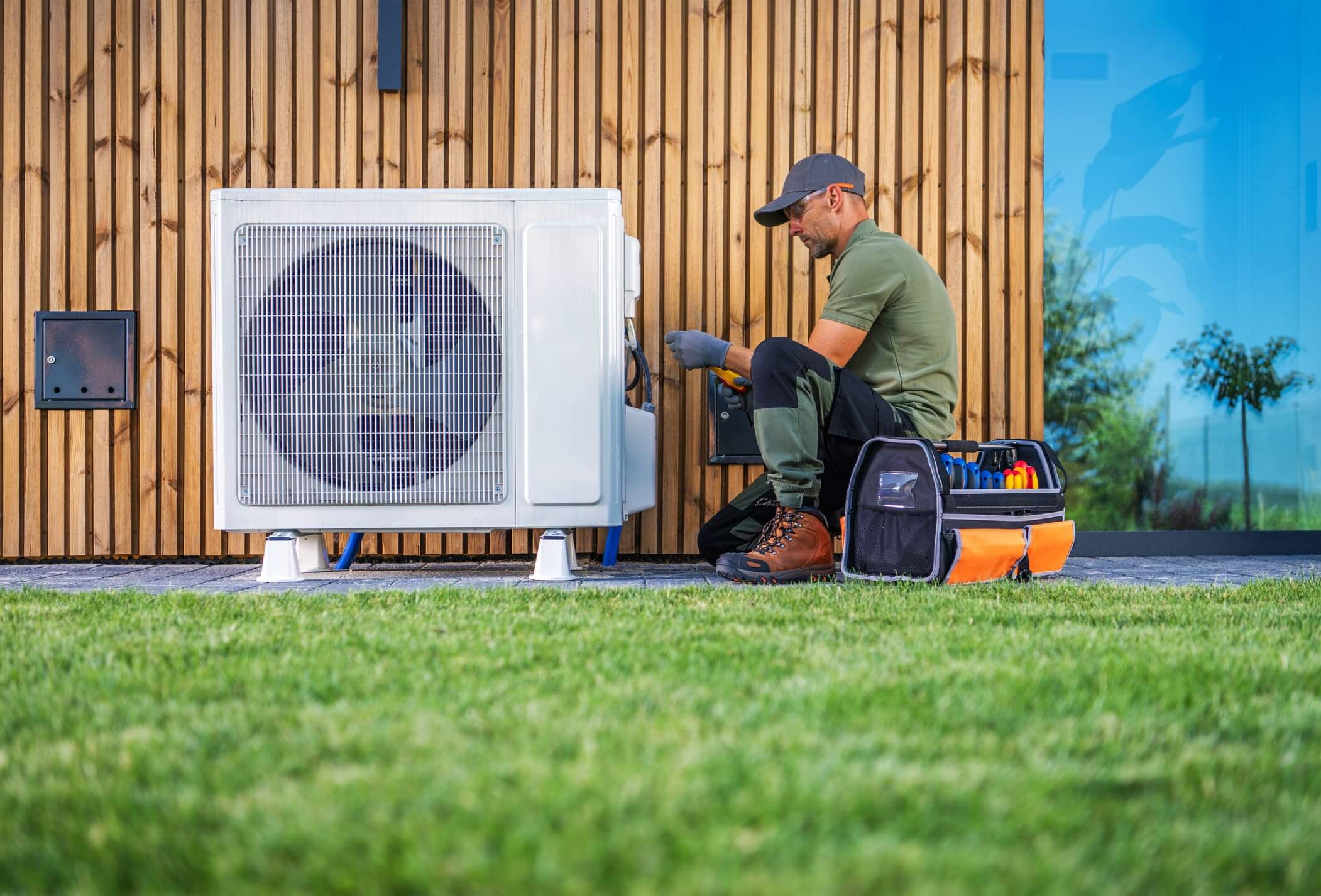 Technician repairing an outdoor air conditioning unit with tools.