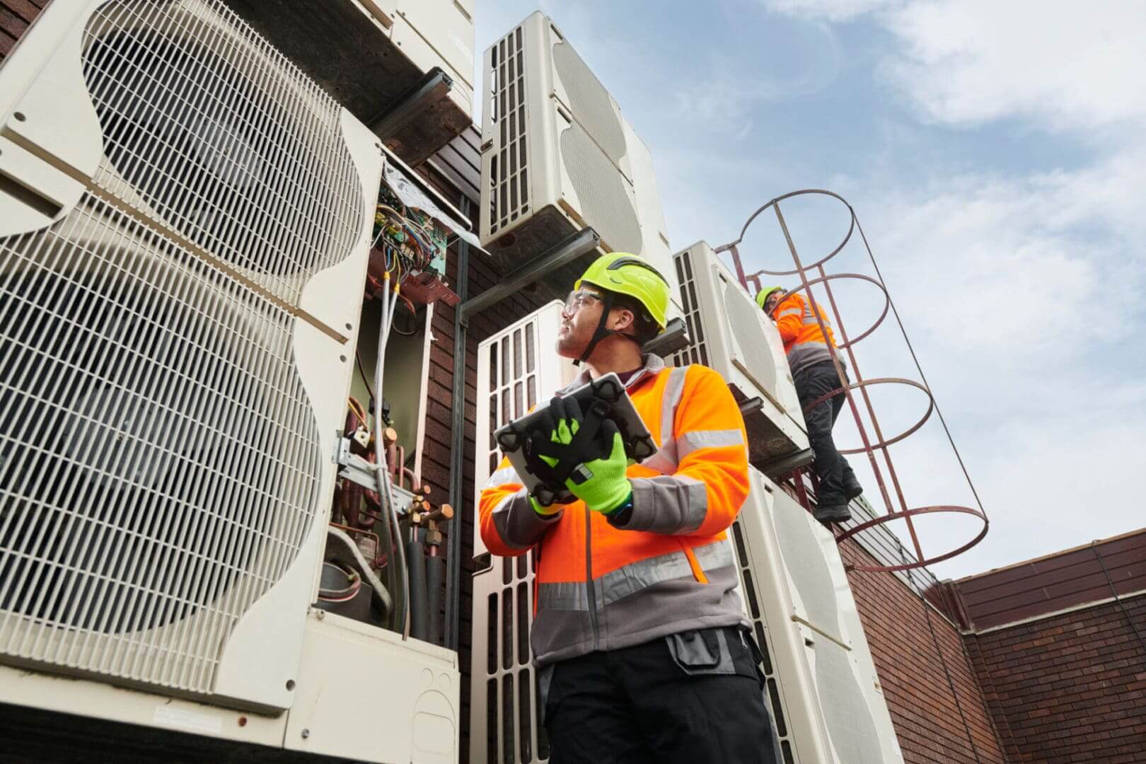 Technicians inspecting rooftop air conditioning units.